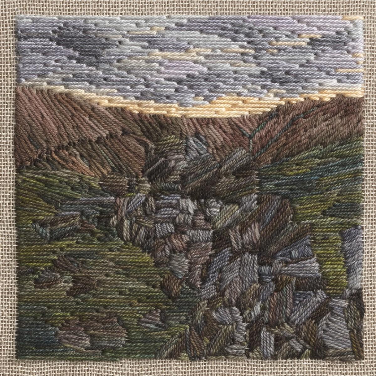 Stitched artwork depicting a dark moorland hillside with a tumble down dry stone wall leading away from the eye. The sun has just set and there is a bright line of sunshine on the horizon beneath grey/purple clouds
