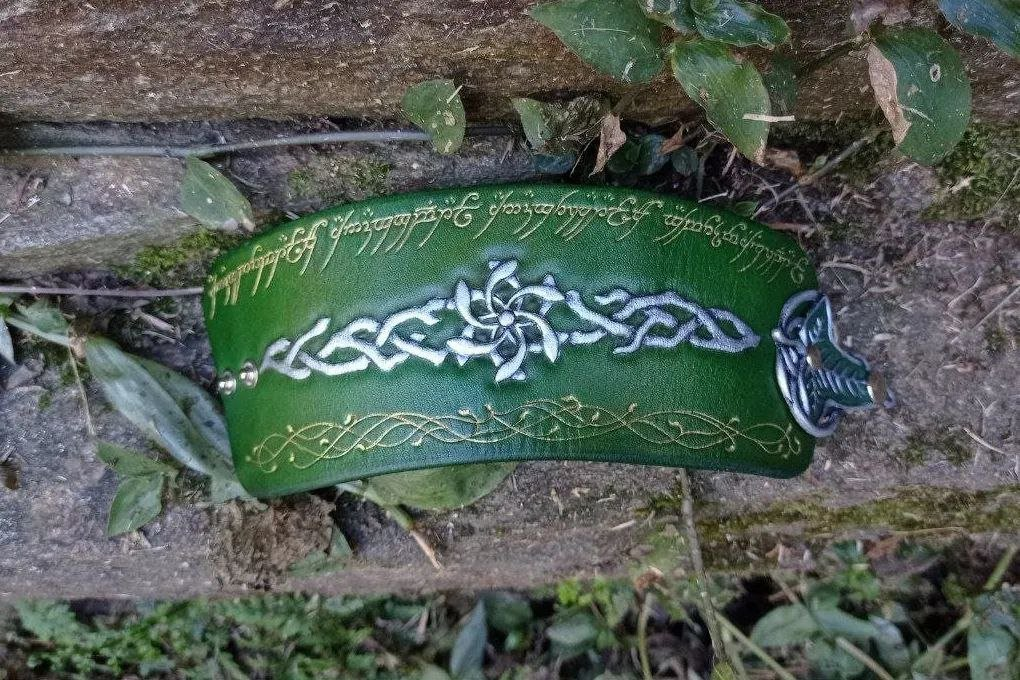 Front pic of the leather cuff, stretched, with a view to the whole design of the inscription, the vines and the Nenya, and partial view of the fastener, a Lórien leaf