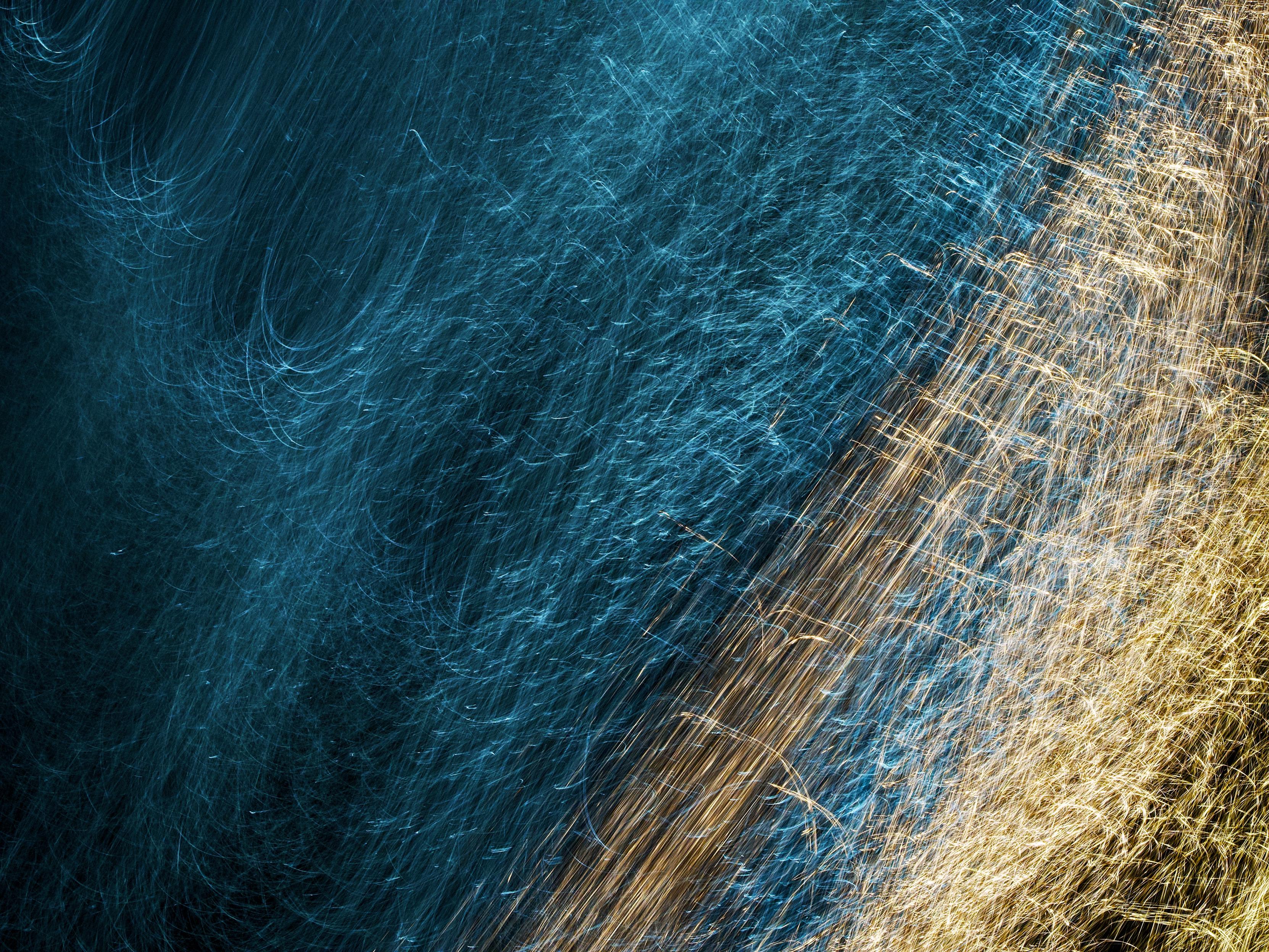 Intentional camera movement and a 1-second exposure creates swirling, scratchy lines of blue and yellow light on the surface of the River Clyde as it runs through Glasgow. Here the blue light dominates the scene while the yellow runs at an angle on the right edge.