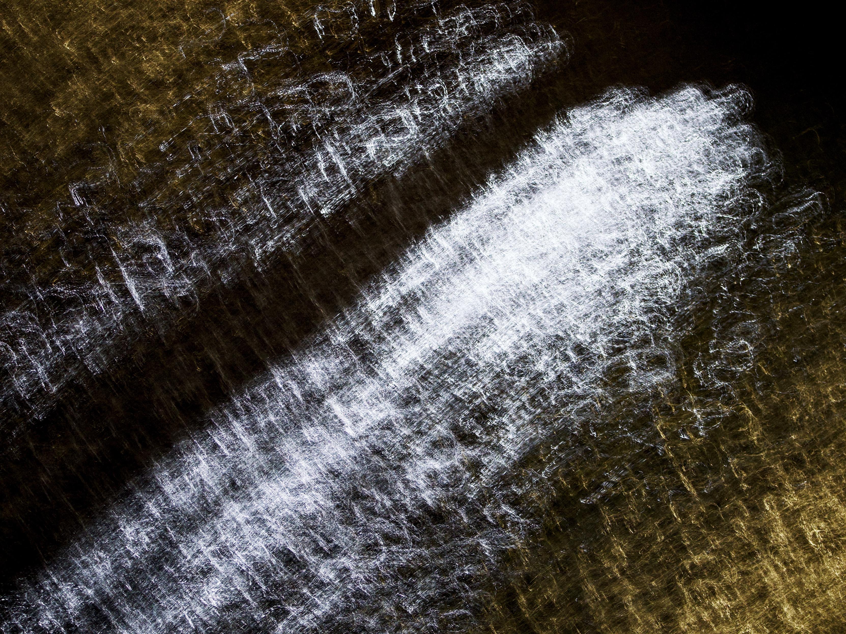 Intentional camera movement and a 1-second exposure creates swirling, scratchy lines of white and yellow light on the surface of the River Clyde as it runs through Glasgow. Here the bright white light dominates the scene while the yellow runs at an angle on the top left and bottom right edges.