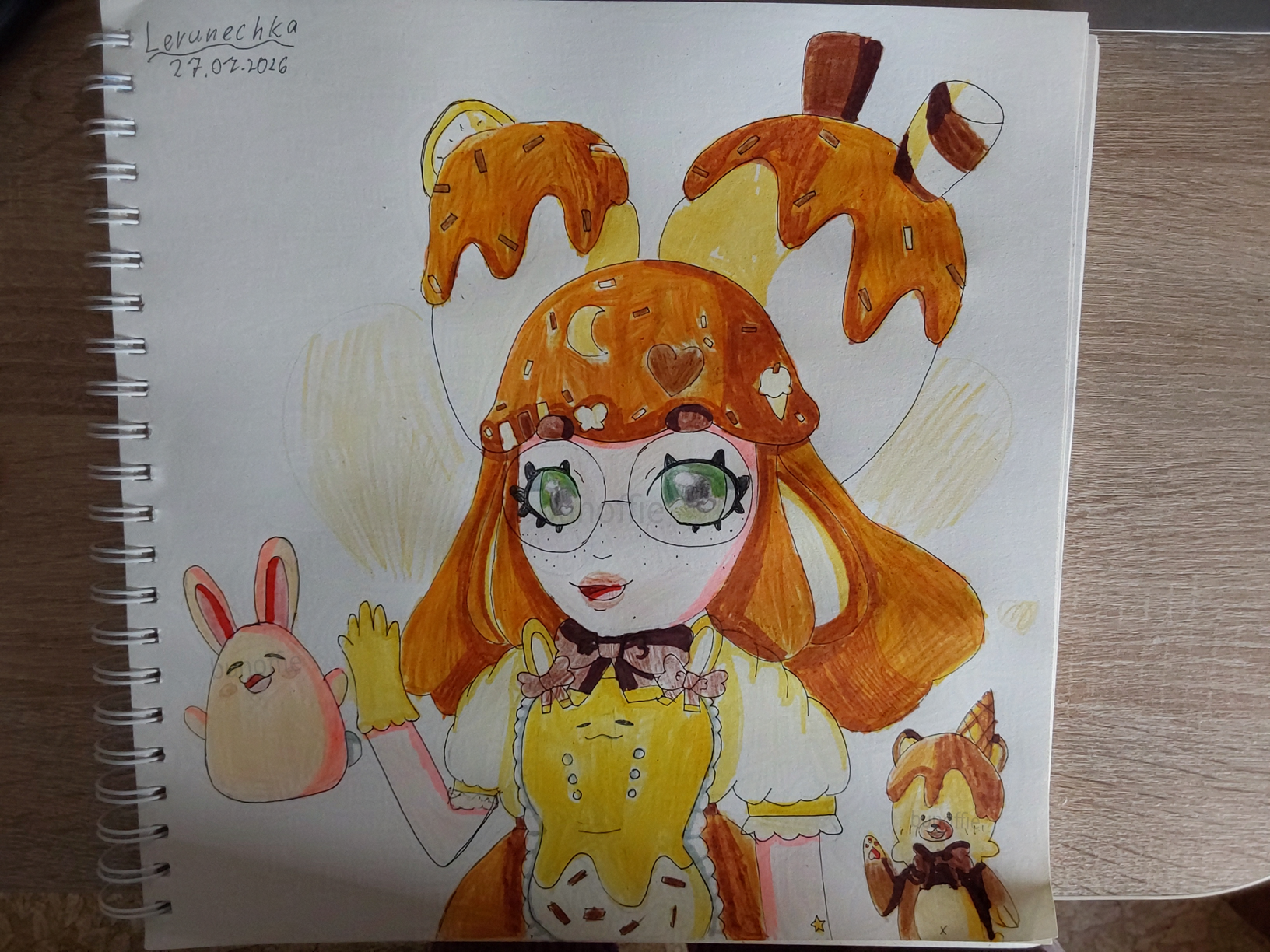 A traditional drawing of a baker with toffee sauce (orangeish brown) wavey hair, green eyes and bunny ears, they have two big buns with toffee drips on their head, one banana slice and the other one two chocolate wafers. They wear a cream blouse, round glasses, yellow apron with bunny ears on it, same colored gloves and orangeish-brown skirt. A cream colored bunny and a bear with yellow face, toffee sauce on and waffle cone on his head and brown body are also shown.