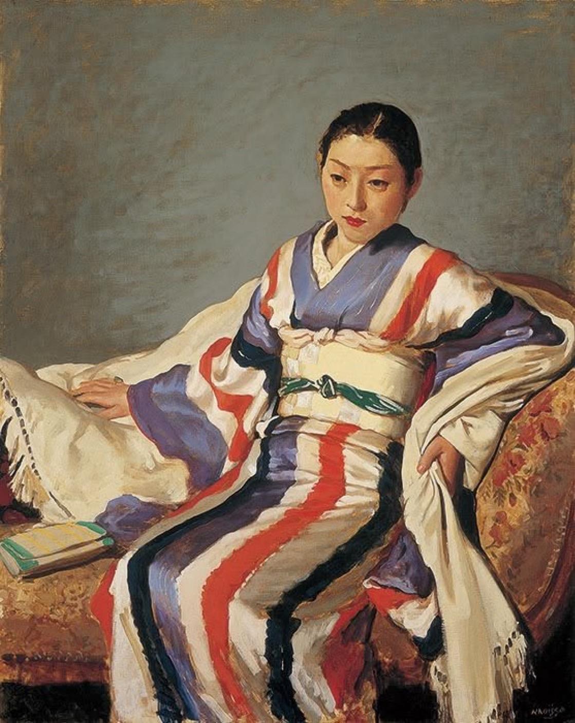 A seated young woman in a colorful kimono with red, blue, and white stripes. She appears contemplative, with her hands resting on her lap. A book lies beside her on a plush couch, against a muted background.
