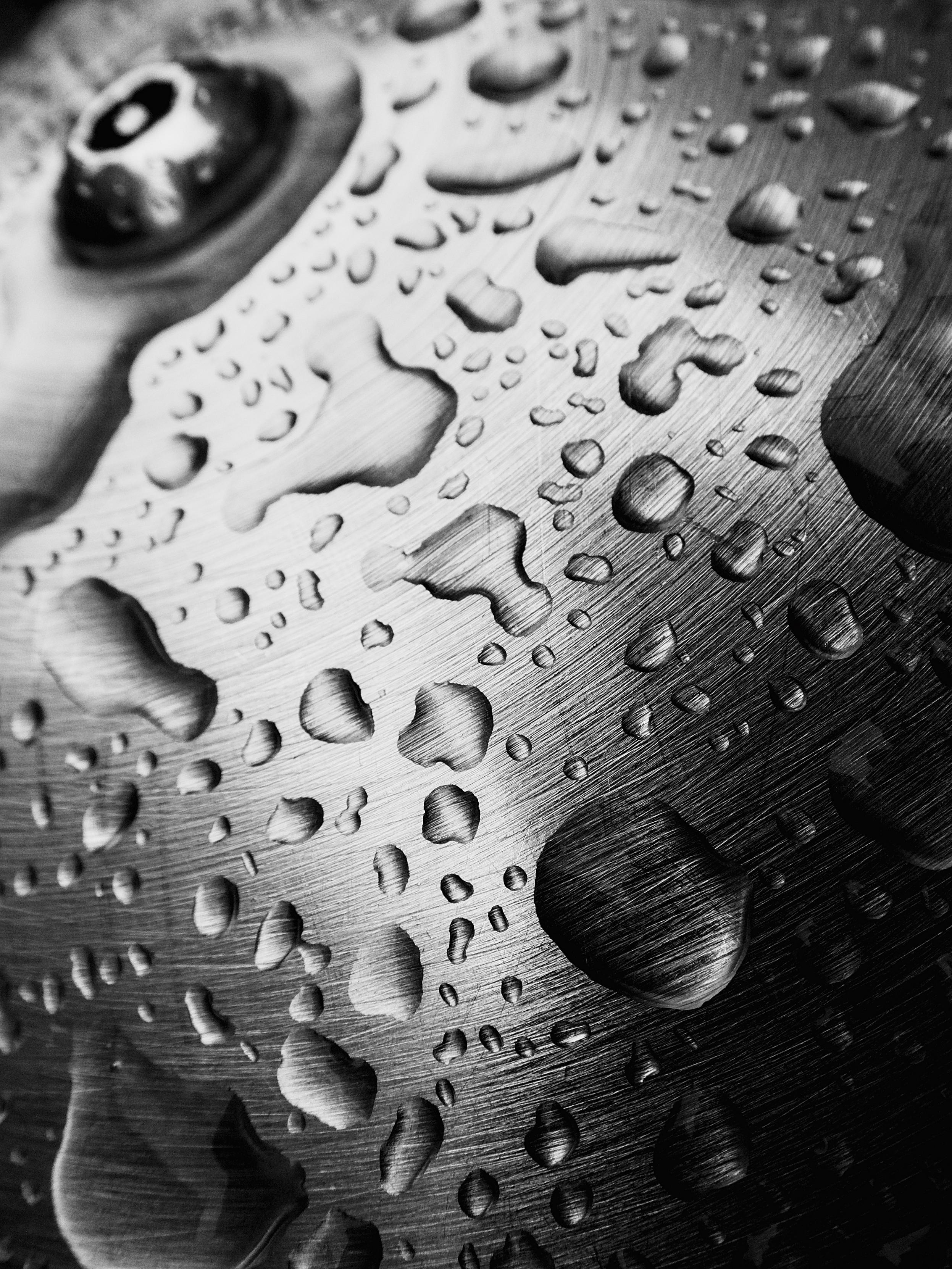 Raindrops pool into abstract shapes on the shiny chrome bollards outside a Glasgow subway station