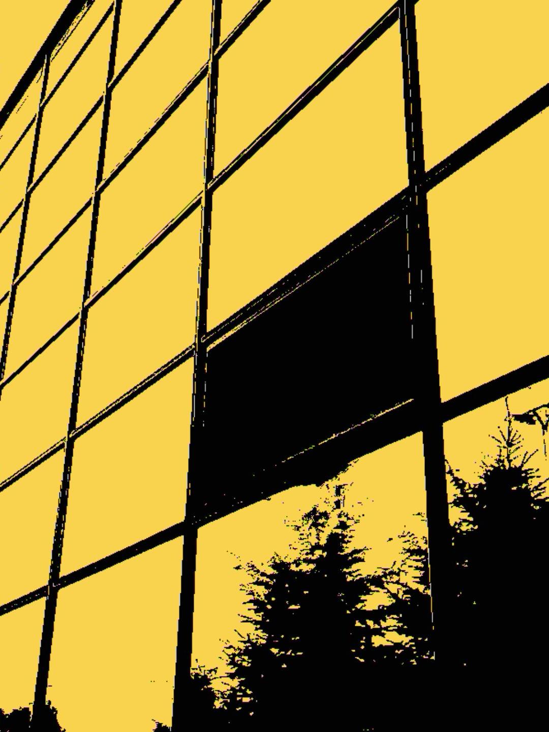 A high-contrast abstract view of a modern glass-and-steel building, with bold black structural lines against a yellow sky. One open window in the glass wall creates a striking black void, contrasting sharply with the surrounding yellow panes, while dark silhouettes of trees appear below. Photographed with a Kodak Charmera.