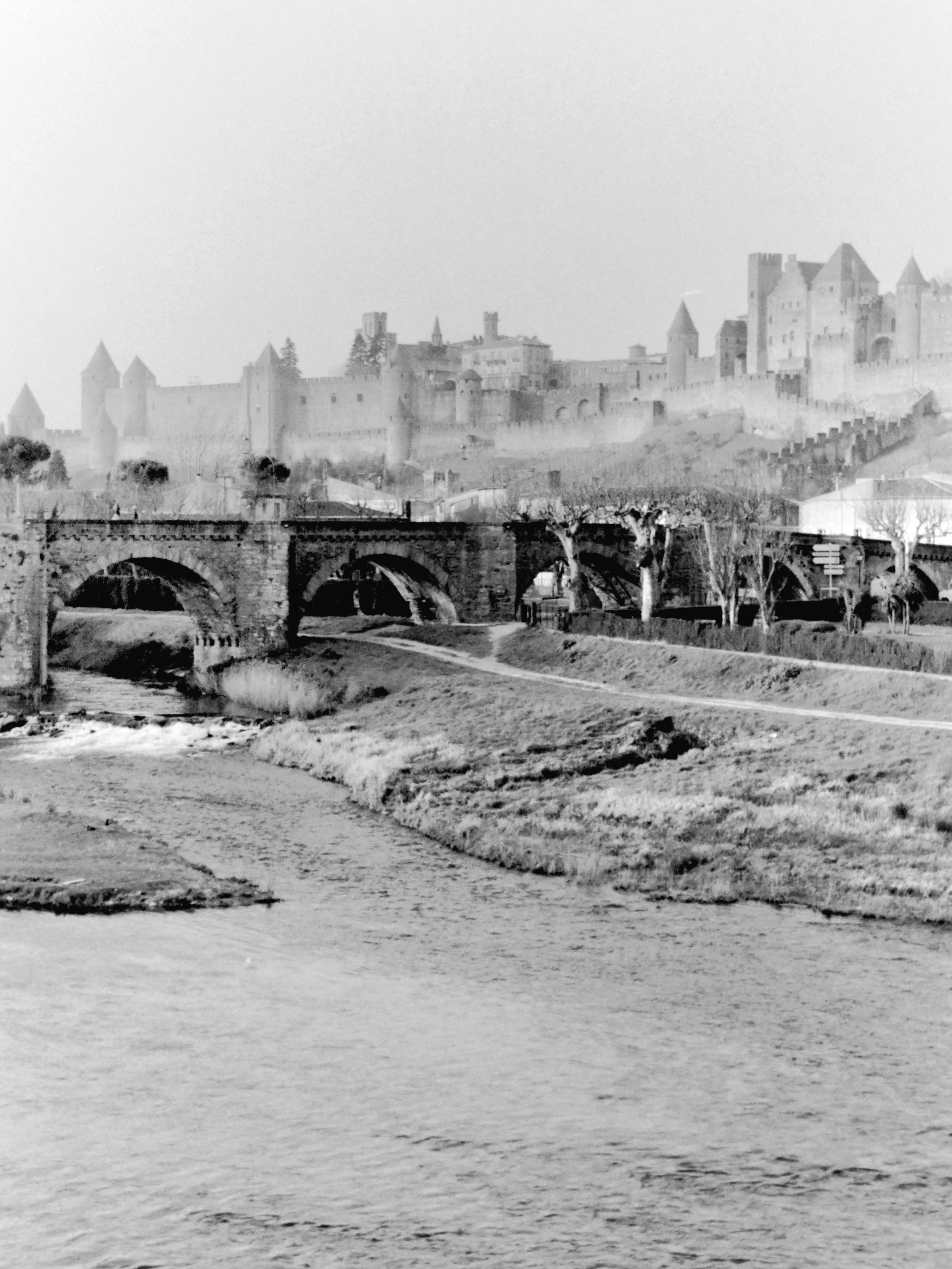"Analog" black and white 3:4 portrait photograph of "La Cité" of Carcassonne, a large walled medieval citadel located in the south of France, restored in the 19th century by the architect Eugène Viollet-le-Duc.