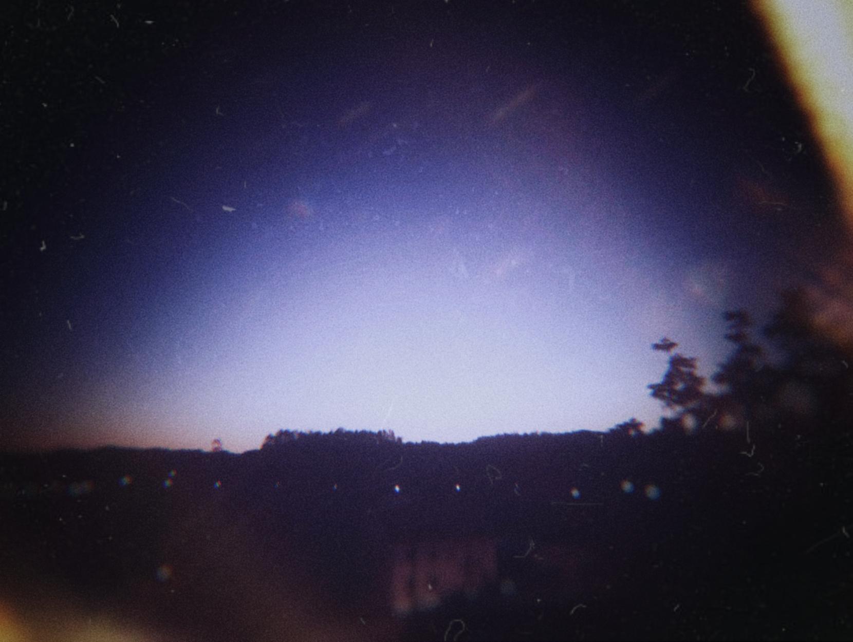 Unha fotografía nocturna dunha paisaxe rural. Foi editada para que semelle ás imaxes feitas con cámaras de xoguete analóxicas: po na imaxe, iluminación e desenfoques estraños, temperatura... É dicir, todo o que non debería pasar na fotografía máis técnica e clásica.