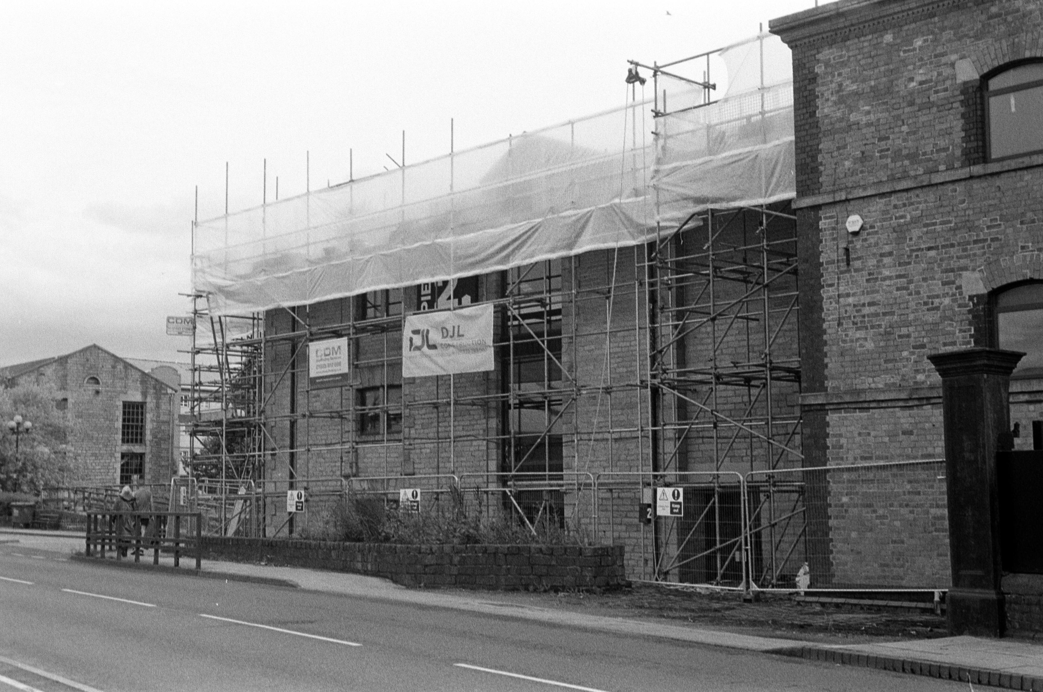 A black and white film photo of roofing work on Pier 2 at the Wigan Pier Quarter of town